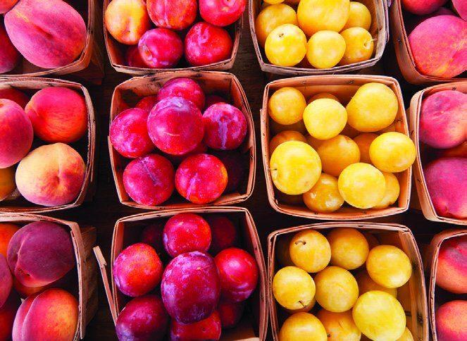 Plums and yellow fruit in wooden baskets